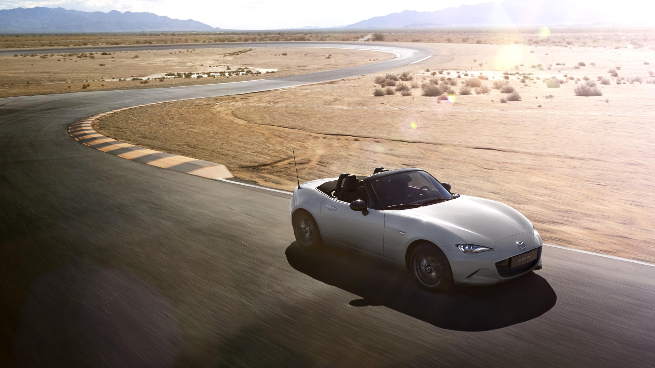 Mazda MX-5 blanco circulando por un circuito en el desierto.